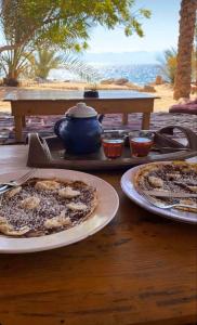 a table with two plates of pizza and a teapot at Big Dune camp in Nuweiba