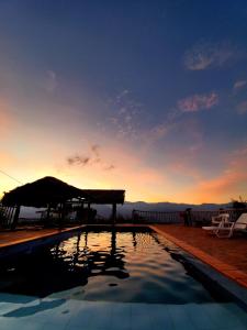 a swimming pool with a sunset in the background at Serrania del Viento in Barichara