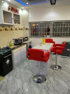 uma cozinha com cadeiras vermelhas e um balcão branco em Residence NOURAH em Rufisque