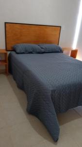 - un lit avec une couette bleue et une tête de lit en bois dans l'établissement Playa del Carmen kassita Bambu, à Playa del Carmen