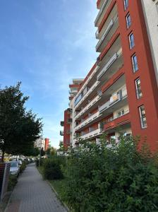 a tall red building with a sidewalk next to a building at Nomad Apartments in Prague