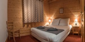 - une chambre avec un lit et un mur en bois dans l'établissement Chalet Portes du Soleil 1, aux Gets