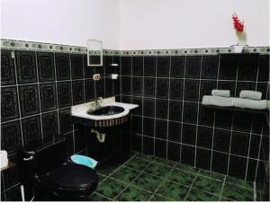 uma casa de banho com azulejos pretos, um WC e um lavatório. em Pura Vida House em Quepos