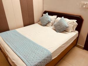 ein Bett mit blauen und weißen Kissen darauf in der Unterkunft The For You Hotel & Restaurant in Rishikesh