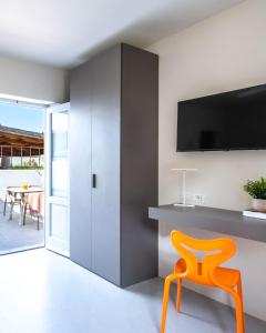 an orange chair in a living room with a tv at Vico San Lorenzo - Camere a Salina in Malfa