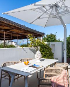 una mesa y sillas blancas bajo una sombrilla blanca en Vico San Lorenzo - Camere a Salina, en Malfa