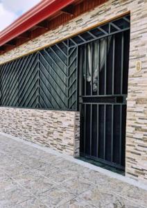 a building with a black gate and a brick wall at Pura Vida House in Quepos