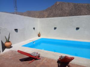 a blue swimming pool in a white wall with two chairs at cabaña merlot in Cafayate