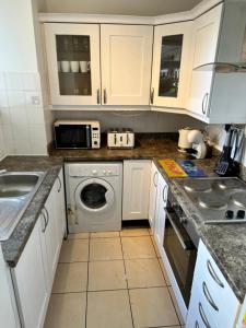 cocina con armarios blancos y lavadora en JB Stays Tooting, en Londres
