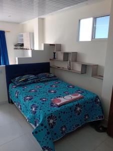 a bedroom with a bed with a blue comforter at Hostal Mi Elvirula in Santa Marta