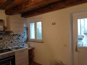 a kitchen with a sink and two windows and a stove at casettina Vittoria in Consiglio di Rumo