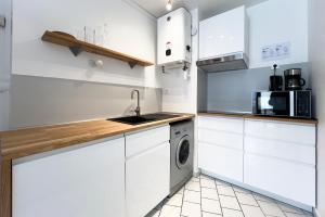 - une cuisine avec des placards blancs et un lave-linge/sèche-linge dans l'établissement Appart T2 proche commerces et NAVAL GROUP, à Cherbourg en Cotentin