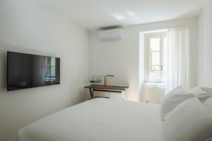 Un dormitorio blanco con una cama y un televisor. en La Vacanza Bellagio, en Bellagio