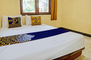um quarto com uma cama grande com almofadas azuis e amarelas em OYO 93107 Homestay H Syarif Syariah – Bandar Gresik em Gresik