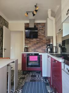 a kitchen with a red stove and a brick wall at Mon nid d'or JOIGNY FRANCE in Joigny