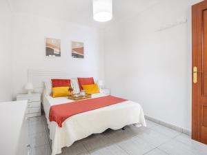 ein weißes Schlafzimmer mit einem Bett mit roten und gelben Kissen in der Unterkunft Live Arico la Jaca el Remo in Arico