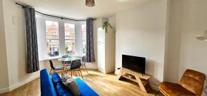 a living room with a blue couch and a tv at Harlequin Apartments by Switchback Stays in Cardiff