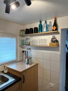 a kitchen with a sink and shelves with bottles at Besoin d'un séjour Détente & Tranquillité avec une vue panoramique ? in Châtillon