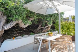 a white table and chairs under an umbrella at Vico San Lorenzo - Camere a Salina in Malfa