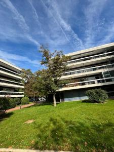 un gran edificio con un árbol delante en Écrin de verdure au Chesnay et parking gratuit, en Le Chesnay