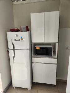 a kitchen with a refrigerator and a microwave at Rooftop 402: cobertura de um quarto no centro in Sete Lagoas