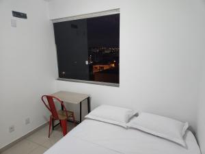 a bedroom with a bed and a table and a window at Rooftop 402: cobertura de um quarto no centro in Sete Lagoas