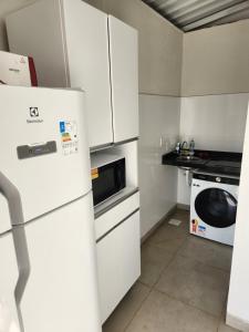 a small kitchen with a refrigerator and a microwave at Rooftop 402: cobertura de um quarto no centro in Sete Lagoas +12 photos