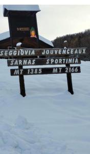 a sign in the snow with a person sitting on it at Alpine House in Sauze dʼOulx