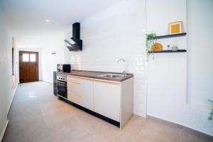 a white kitchen with a sink and a stove at Casas Rurales Complejo AIRES DEL JÚCAR in Alcalá del Júcar