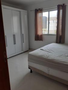 a bedroom with a bed and cabinets and a window at apartamento praia dos milionarios in Ilhéus