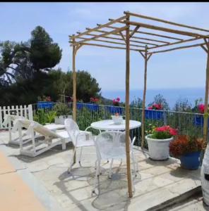 a wooden pergola with a table and chairs on a patio at Message in a Bottle Bed and Breakfast in Camporosso
