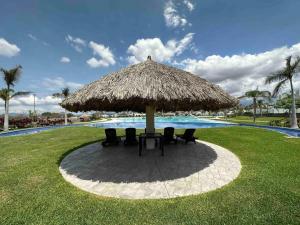 uma mesa e cadeiras debaixo de um guarda-sol de palha ao lado de uma piscina em ¡Date un break del estrés! em Oaxtepec
