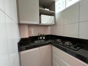 a kitchen with white cabinets and a sink and a stove at Apartamento dos Sonhos - Studio em Prédio a Beira Mar in Balneário Camboriú +18 photos