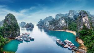 a group of boats docked in a river with mountains at Minh Hằng Cruise in Ha Long
