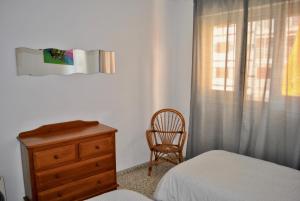 1 dormitorio con cama, silla y vestidor en Apartamento Benicasim 1ª línea de playa, en Benicàssim