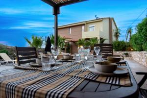 - une table avec des assiettes et des verres sur la terrasse dans l'établissement Cicada 4 Bedroom Villa, à Palaiokastro