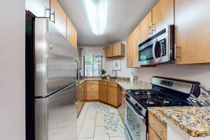 a kitchen with stainless steel appliances and wooden cabinets at Pacific Cove Unit 111 in Los Angeles