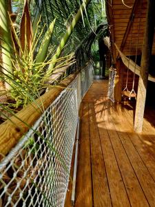 une terrasse en bois avec un hamac et des plantes. dans l'établissement PURA VIDA Lodge Cabane perchée, à Sainte-Rose