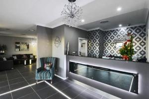 a living room with a fireplace and a chandelier at Astro Dish Motor Inn in Parkes