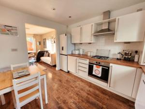 cocina con armarios blancos, mesa y encimera en Modern 5 Bedroom Townhouse with Free Parking, en Glasgow