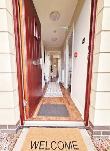 um corredor com uma porta com um sinal de boas-vindas em Modern 5 Bedroom Townhouse with Free Parking em Glasgow