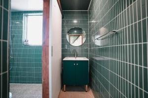 a green tiled bathroom with a sink and a mirror at Stay Ccassette Player in Mokpo