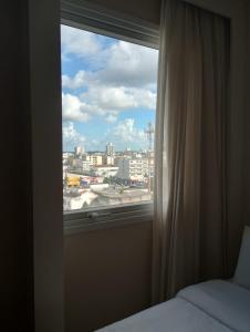 a bedroom window with a view of a city at Quarto 501 do Design Hotel Linhares in Linhares