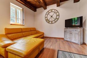 a living room with a couch and a clock on the wall at Apartmány - Chata Zadov in Prachatice