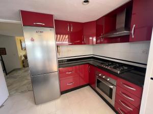 a kitchen with red cabinets and a stainless steel refrigerator at Casa de Playa in Estepona