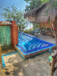 a swimming pool next to a house with a hut at Beach House-Casita in Calatagan with pool ( for 6) in Calatagan