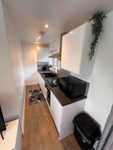 a small kitchen with white cabinets and a microwave at Minster Hilltop Apartment in Minster