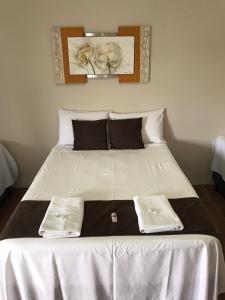 1 cama blanca grande con 2 toallas blancas. en Pousada Sabia Capitolio, en Capitólio
