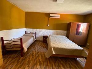 twee bedden in een kamer met gele muren en houten vloeren bij Casa en pinar del norte san luis in Barranca Colorada