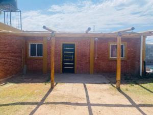 een rood bakstenen gebouw met een zwarte deur erop bij Casa en pinar del norte san luis in Barranca Colorada
